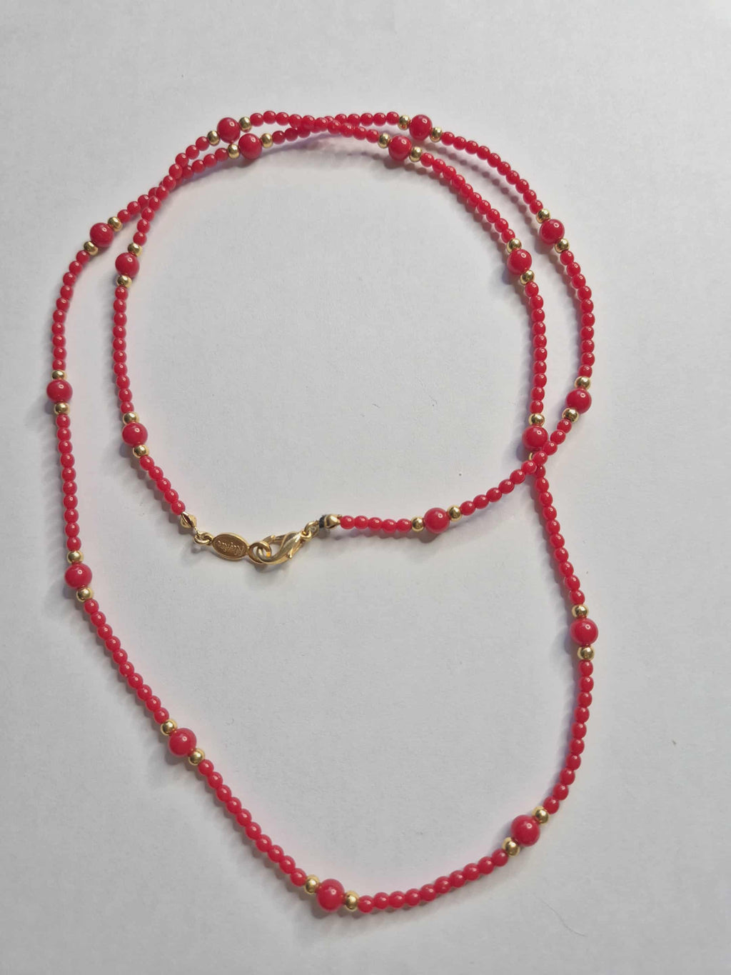 Napier raudoni karoliai su auksinėmis detalėmis