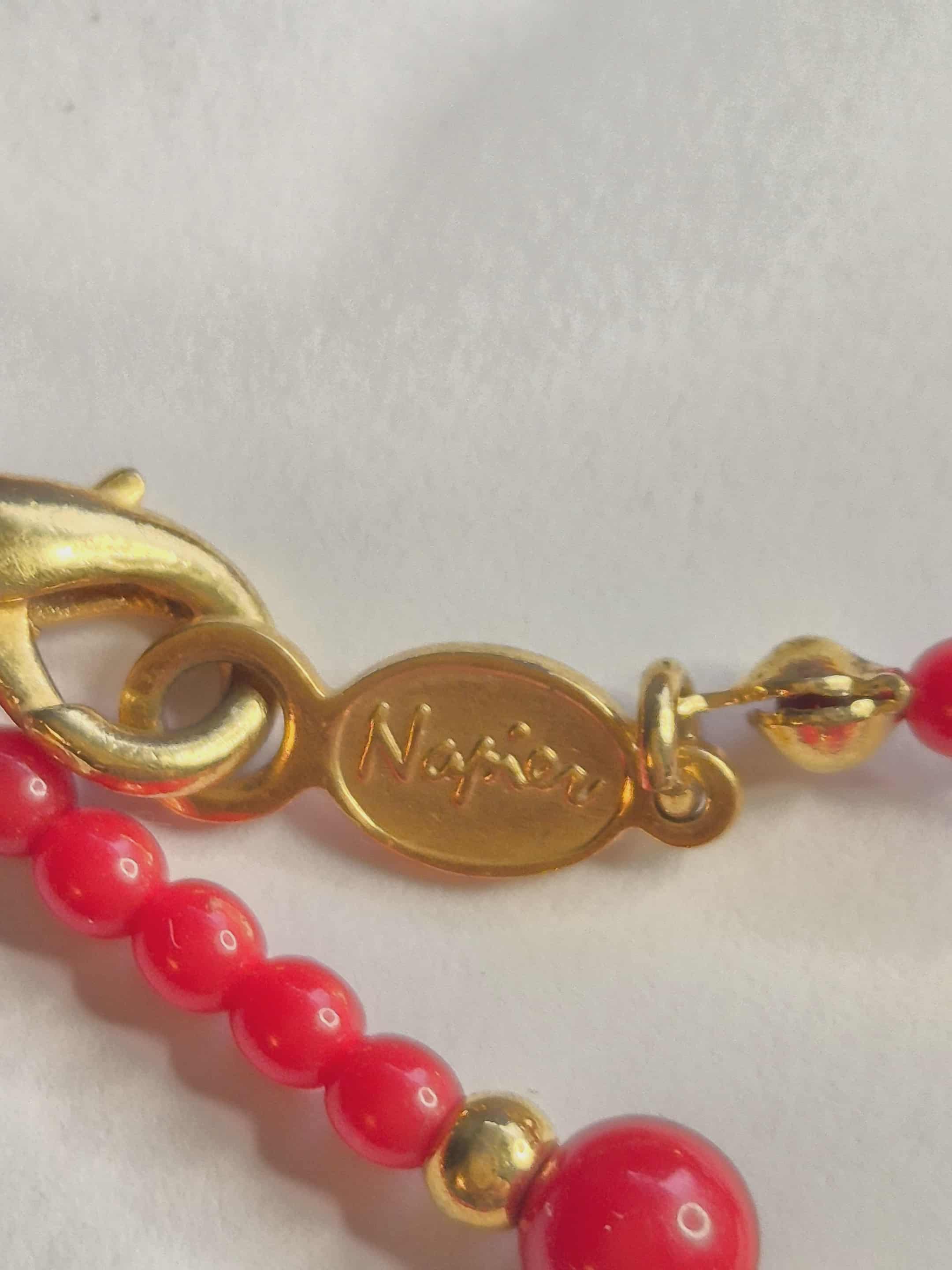 Napier raudoni karoliai su auksinėmis detalėmis