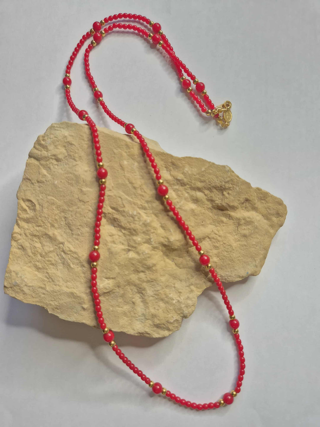 Napier raudoni karoliai su auksinėmis detalėmis